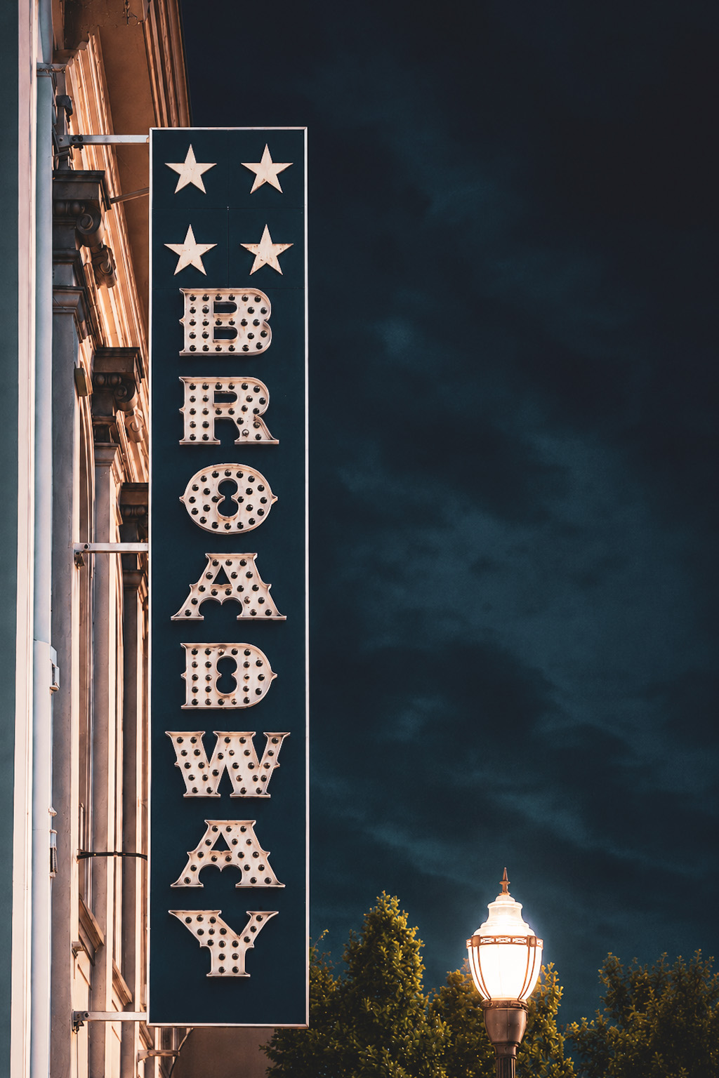 The BROADWAY marquee at dusk, a streetlamp glowing beside it